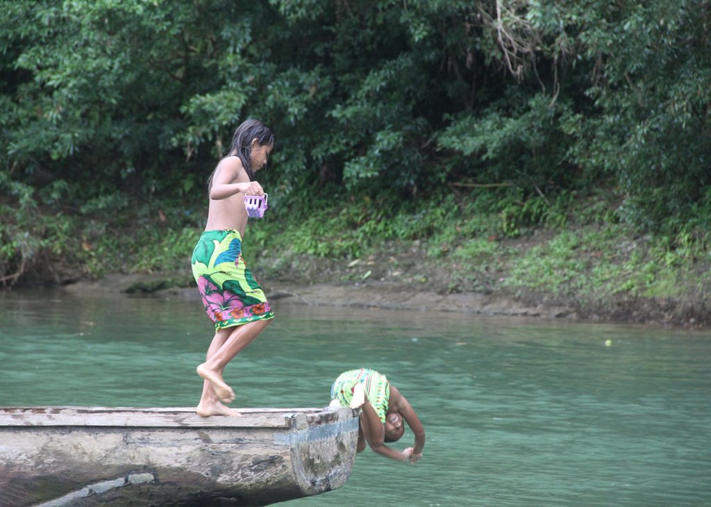 enfants sautant dans l'eau d'un bateau en bois